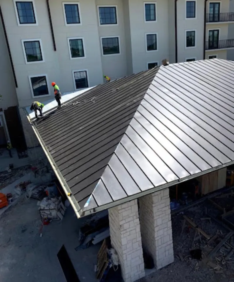 Crew installing standing seam metal roof panels on a commercial project in Hutchison